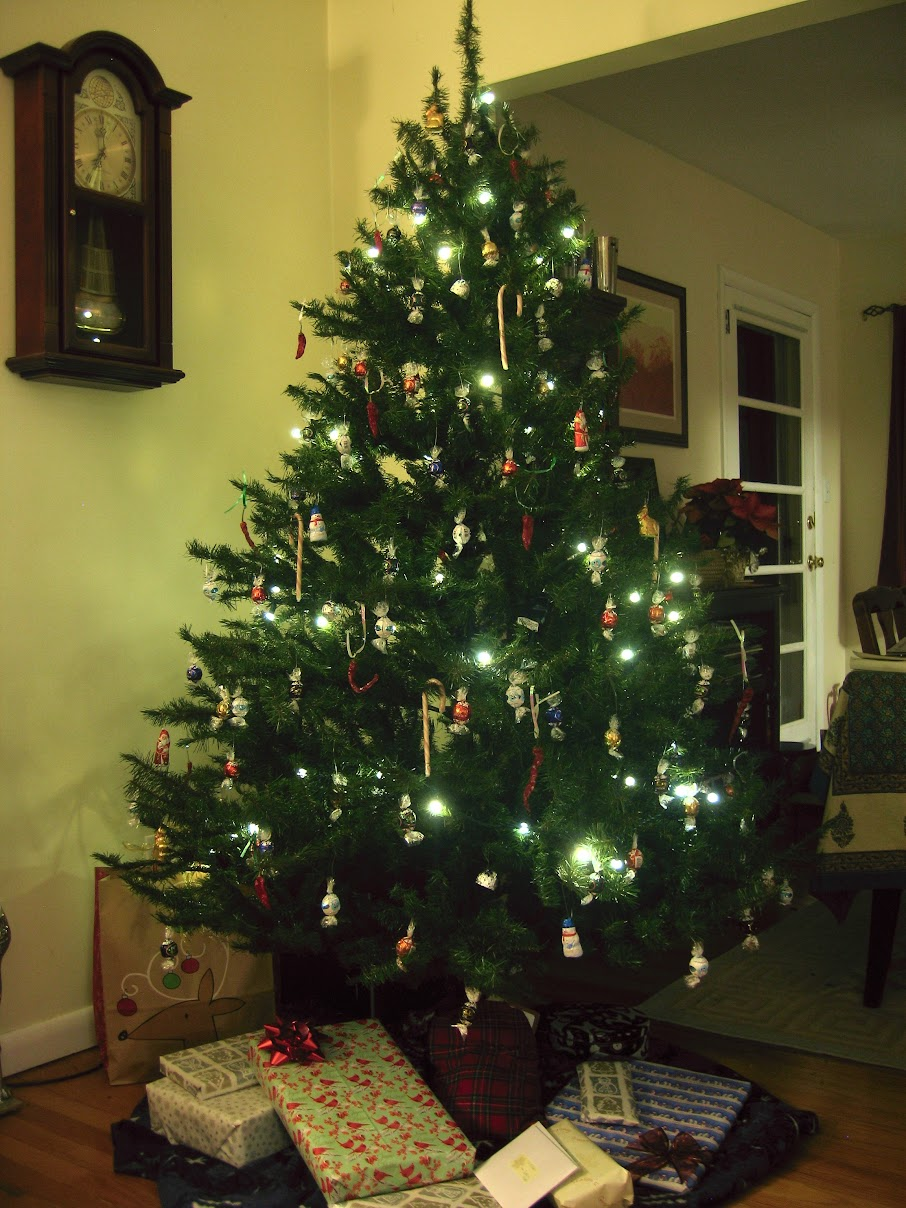 Christmas tree decorated entirely with edible ornaments — candy canes, chocolates, and food-shaped decorations, with wrapped presents underneath