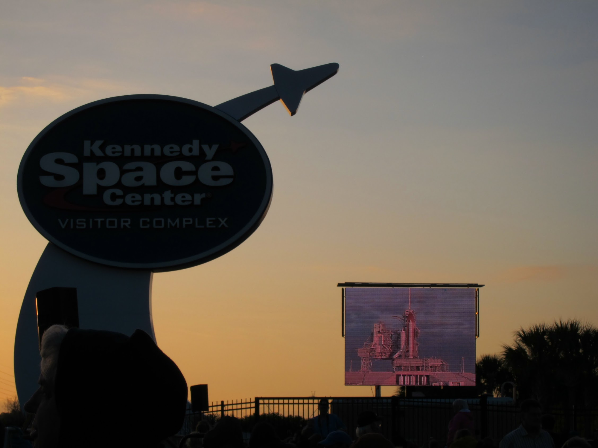 Kennedy Space Center sign at sunrise with Space Shuttle on screen