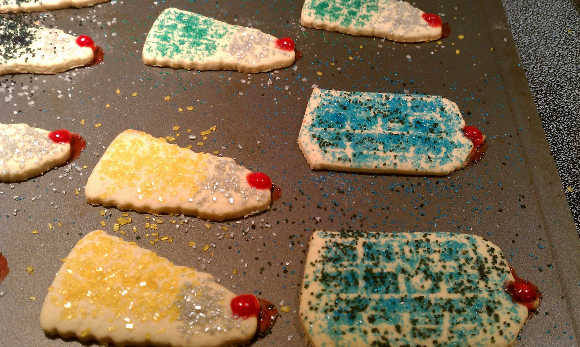 Dalek and Tardis sugar cookies on a baking sheet, decorated with blue and green colored sugar