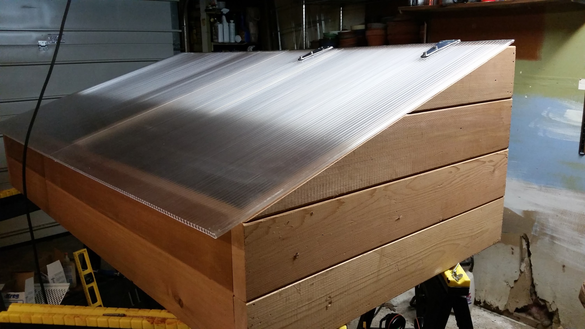 Completed cold frame in the garage — cedar box with corrugated polycarbonate lid on hinges
